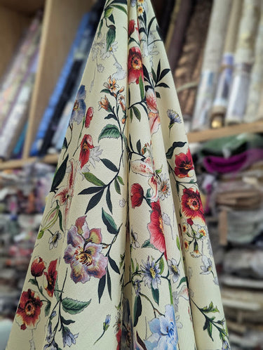 Floral fabric with red, purple, and blue flowers on a cream background draped within a shop setting.