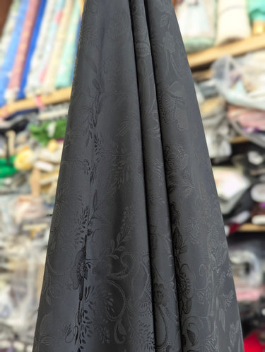Black fabric with floral pattern draped in a store setting