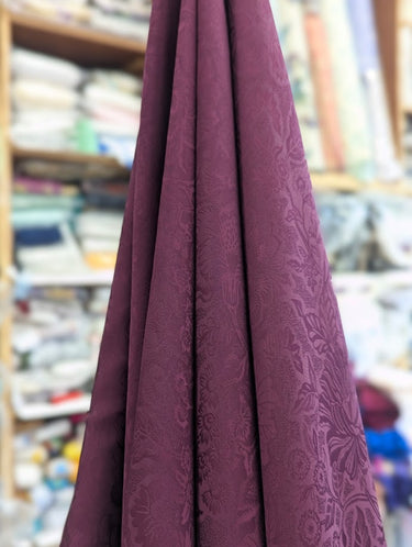 Close-up of purple fabric with a pattern draped in a store setting