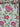 A bolt of fabric with a floral pattern of red and pink flowers and green leaves on a white background.