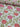 A bolt of fabric with pink and red flowers and green leaves on a white background