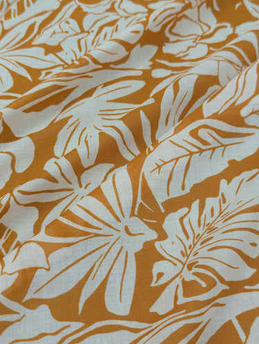 Close-up of a printed pure cotton fabric with ivory botanical print on a mustard base.