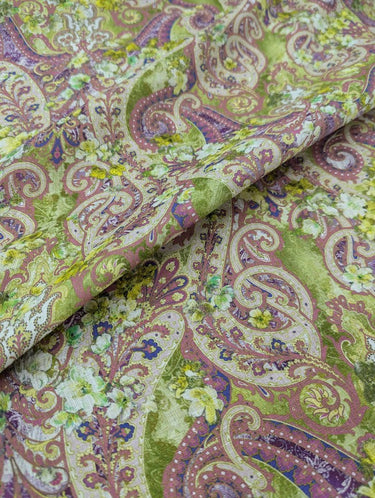 A linen fabric with an intricate paisley pattern in warm, earthy tones of muted greens, purples, and pinks, accented by floral motifs.