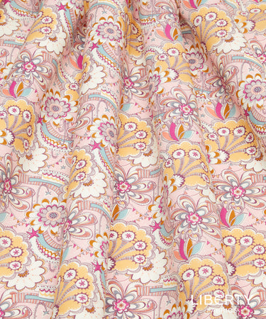 A close-up of draped fabric with a dense floral and paisley print in soft pink, yellow, white, teal, and brown. The fabric fills the entire frame, with a 'LIBERTY' watermark visible in the bottom right corner.