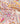 A close-up of a patterned fabric featuring a retro floral and paisley design in pink, orange, yellow, and white, with a Liberty Fabrics logo in the bottom right corner.