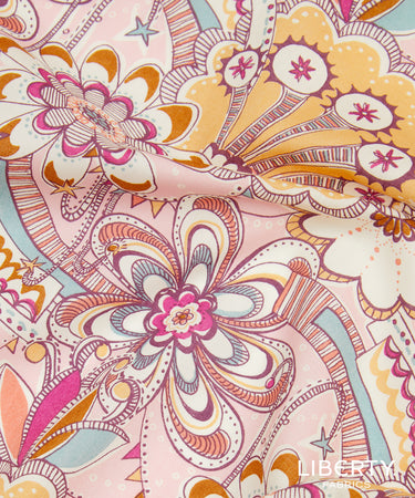 A close-up of a patterned fabric featuring a retro floral and paisley design in pink, orange, yellow, and white, with a Liberty Fabrics logo in the bottom right corner.