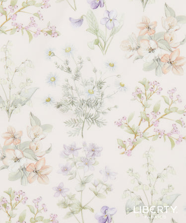Liberty Fabrics floral watercolor pattern featuring delicate pastel flowers and foliage on a warm off-white background, with the Liberty Fabrics logo in the bottom right corner.