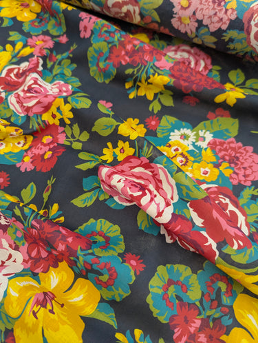 Colorful floral fabric with pink, yellow, and red flowers on a dark background