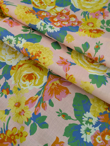 Colorful floral fabric with yellow, pink, and green flowers on a light pink background.