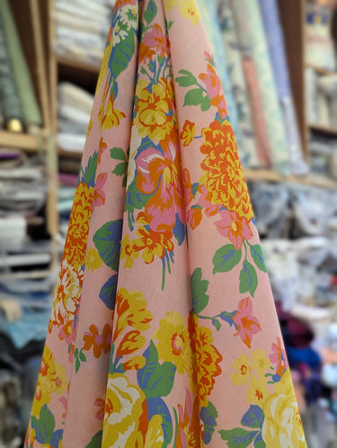 Floral fabric with yellow, pink, and green flowers on a pink background.