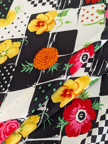Colorful floral pattern on a black and white checkered silk crepe de chine fabric