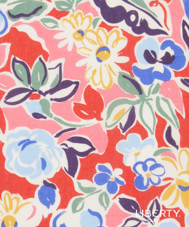 A close-up of a Liberty brand fabric pattern featuring a colorful floral design on a coral red background with white, blue, yellow, and green elements.