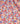 A close-up of a draped fabric with a dense floral print. The pattern features blue, yellow, and white flowers with green leaves on a bright coral-red background.