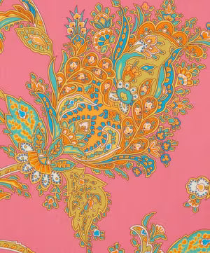 A close-up of a paisley pattern with ornate floral and teardrop motifs in orange, teal, yellow, and white on a pink background.