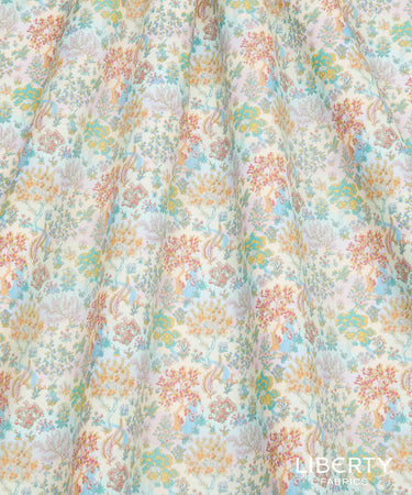 A close-up of a lightweight fabric with a dense, multicolored floral and botanical pattern on a cream background, featuring soft blue, peach, yellow, and pink details. A 'LIBERTY FABRICS CO.