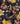 A close-up of a draped fabric with a dark navy background and a floral pattern featuring yellow, pink, and red blossoms with beige leaves. The brand name 'LIBERTY FABRICS' is visible in the bottom right corner.