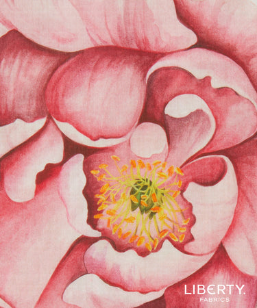 A close-up of a pink peony fabric print by Liberty Fabrics, featuring detailed watercolor-style petals and a yellow-orange center.