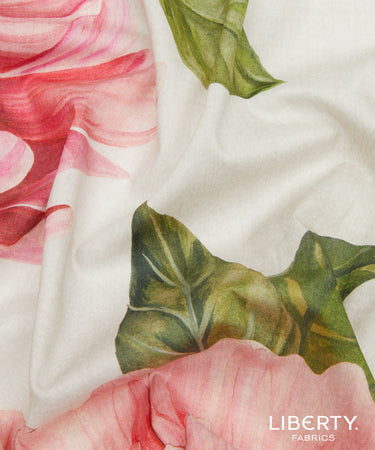 A close-up of Liberty Fabrics featuring a watercolor floral print with pink roses and green leaves on a white background, with the brand logo in the bottom right corner.
