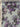 Floral patterned fabric with purple and grey flowers on a light blue background, featuring the selvedge with the brand 'Carnet' and 'Made in Italy'.