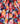 A close-up of draped fabric with a vibrant watercolor-style abstract print in red, pink, orange, yellow, teal, blue, purple, and white.