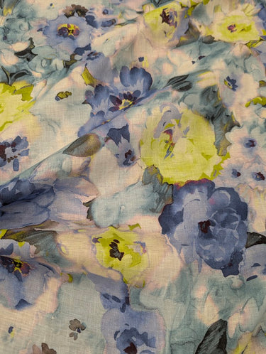 A linen fabric featuring a floral pattern with shades of blue, yellow, and grey, giving an impressionist garden look.