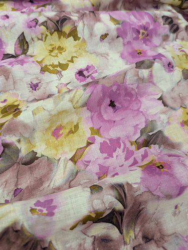 A close up of a linen fabric featuring a floral print with soft colours like pink and yellow