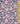 A close-up of a colorful paisley and floral patterned fabric with a gold ruler along the right edge for scale. The design features intricate motifs in pink, teal, orange, yellow, and white on a dark navy background.
