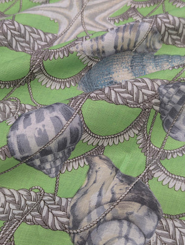 Close-up of fabric with nautical pattern featuring shells and ropes on a green background