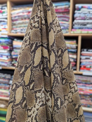 A silk-blend cotton batiste fabric with a snake skin pattern, draped within a shop setting.