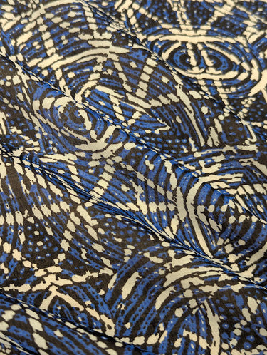 Close-up of a printed pure cotton batiste, with a geometric motif in cobalt blue, ivory, and black, with interlocking circles and angular lines.