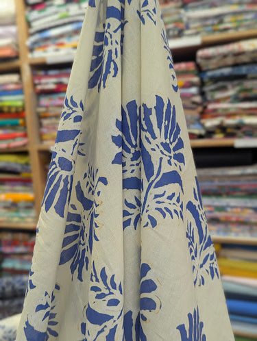 Printed pure cotton fabric with an ivory ground and blue floral motifs draped in a store setting