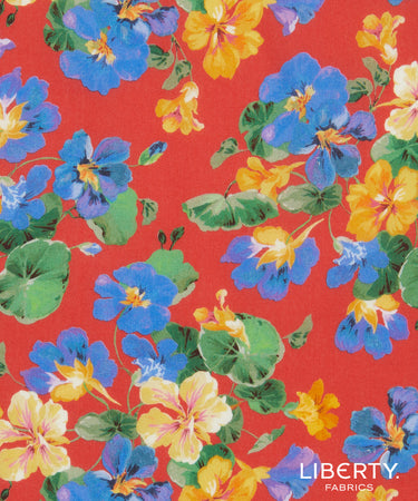 A close-up of Liberty Fabrics floral pattern featuring blue, yellow, and purple flowers with green leaves on a bright red background.