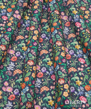 A close-up of a dark navy floral fabric with a dense, multicolored print of flowers and green leaves.