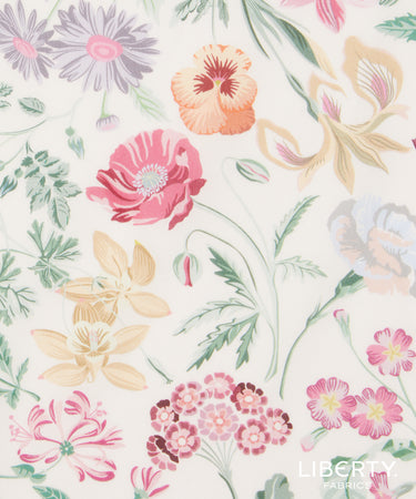 A close-up of a floral fabric pattern featuring pink, peach, purple, and yellow flowers with green leaves on a warm off-white background. The Liberty Fabrics logo is visible in the bottom right corner.