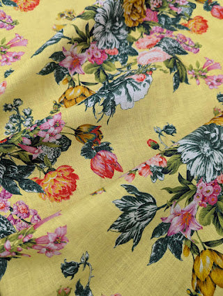 Close up of floral patterned fabric with colourful flowers and leaves on a yellow background