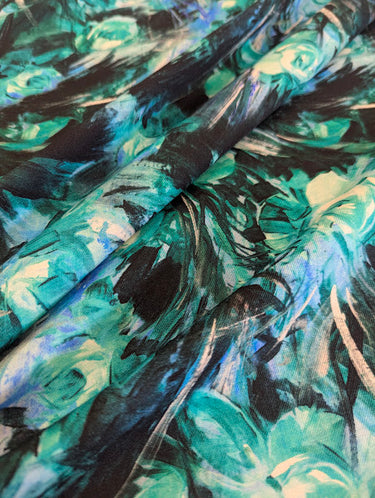 Close-up of a pure wool fabric with painterly florals in green, black, and blue.