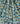 A close-up of draped fabric with a dense tropical print featuring teal, navy, green, beige, and white floral and palm motifs. The Liberty Fabrics logo is visible in the bottom right corner.