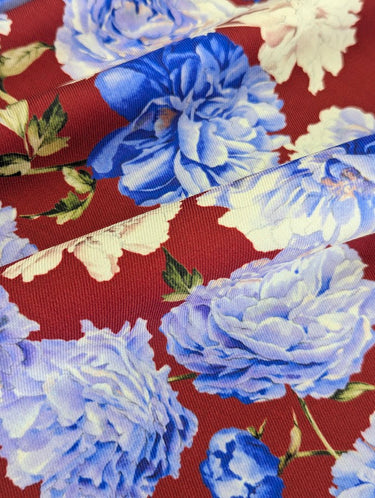 Close-up of a pure wool fabric with blue and white flowers on a red background
