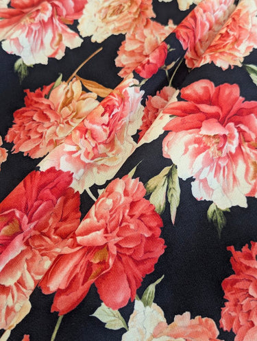Close-up of printed pure wool fabric with pink and red flowers on a dark navy background