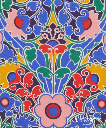 A close-up of a colorful Liberty Fabrics patterned fabric featuring a symmetrical, hand-drawn style floral and scroll design in blue, pink, red, green, yellow, and purple.