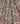 A close-up of Liberty Fabrice floral fabric with a dense, multicolored pattern of pink, orange, green, blue, and purple flowers on a muted sage background.