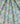 A close-up of draped fabric with a dense, multicolor floral and botanical print on a light blue-green background. The print features pink, yellow, orange, purple, and green flowers and leaves.