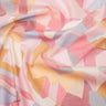 A close-up of draped Liberty Fabrics featuring a pastel geometric pattern with pink, peach, yellow, and light gray shapes.