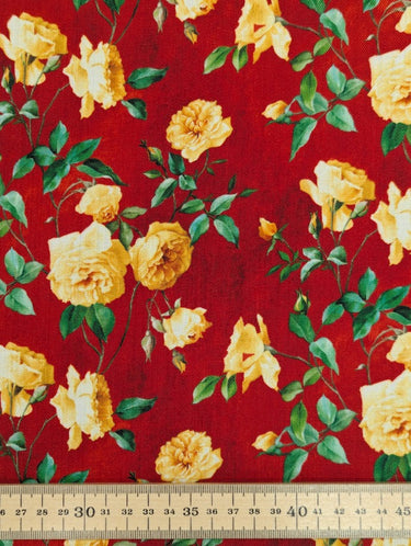 Close-up of a printed wool fabric with yellow flowers on a red background, shown with a ruler at the bottom for scale.