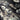 Close-up of a silk chiffon fabric with a foil printed floral design in champagne, silver and grey on a black base.