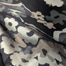 Close-up of a silk chiffon fabric with a foil printed floral design in champagne, silver and grey on a black base.