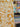 A printed pure cotton fabric with ivory botanical print on a mustard base, shown draped within a store setting to show the transparency of the fabric.