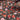 A close up view of silk satin fabric with a floral pattern in shades of red and copper on a brown background.