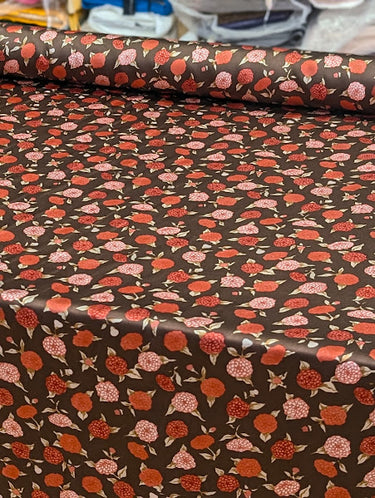 Roll of floral-patterned paper with red and pink flowers on a brown background.