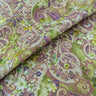 A linen fabric with an intricate paisley pattern in warm, earthy tones of muted greens, purples, and pinks, accented by floral motifs.